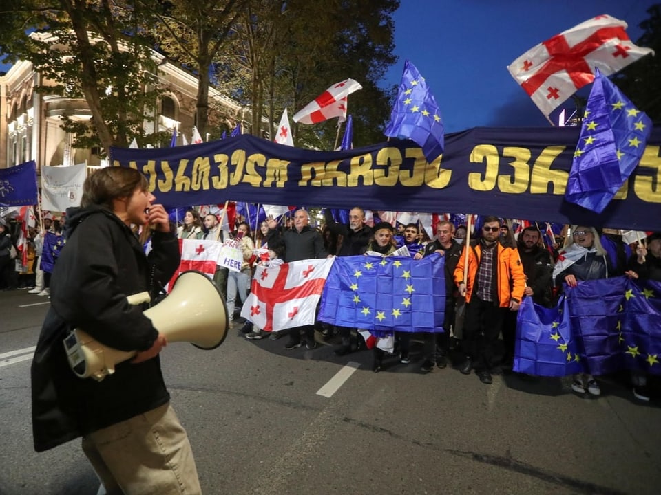 Menschenmenge mit Fahnen, darunter EU- und Georgienflaggen, bei einer Demonstration.