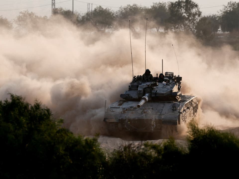 Panzer fährt durch Staubwolken, Bäume im Vordergrund.