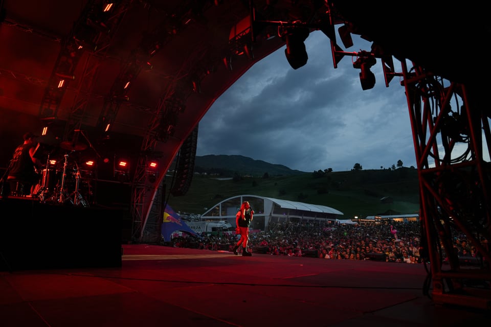 Bühne bei Abendwolkigem Festival mit Publikum und Bergen im Hintergrund.