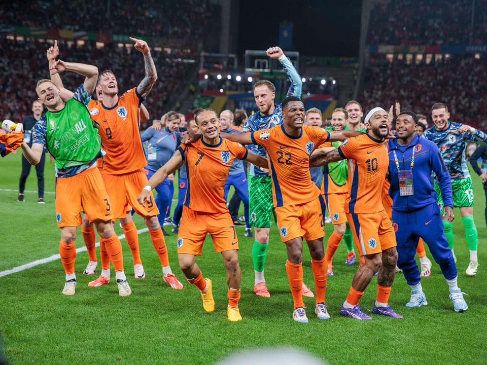 Niederländische Fussballmannschaft feiert nach einem Spiel auf dem Spielfeld.