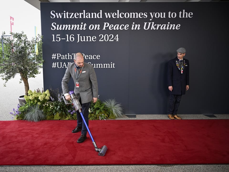 Person reinigt roten Teppich bei Gipfeltreffen für Frieden in der Ukraine 2024.
