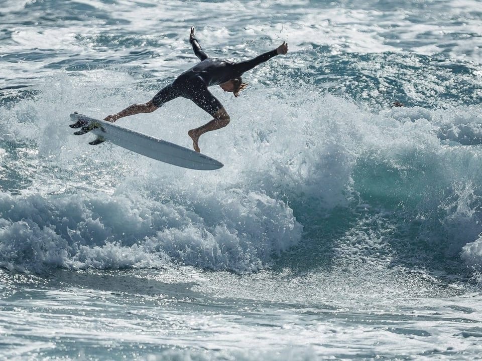 Surfer springt von Welle in der Brandung.