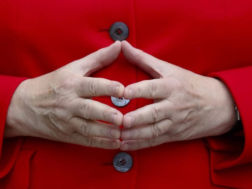 Handstellung von Merkel: Fingerspitzen auf Fingerspitzen und Hände gespreizt
