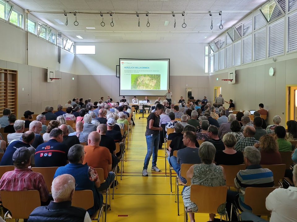 Menschen sitzen in Turnhalle