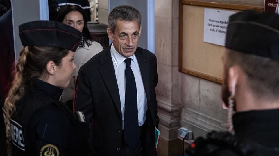 Sarkozy steht neben französischem Sicherheitspersonal.