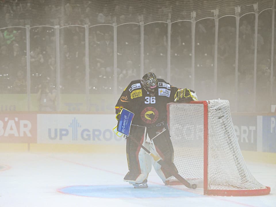 Eishockey-Torwart lehnt sich gegen das Tor im Nebel.