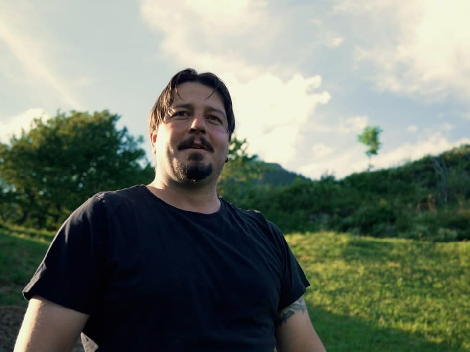 Ein Mann mit dunklen Haaren und schwarzen TShirt auf der Alp