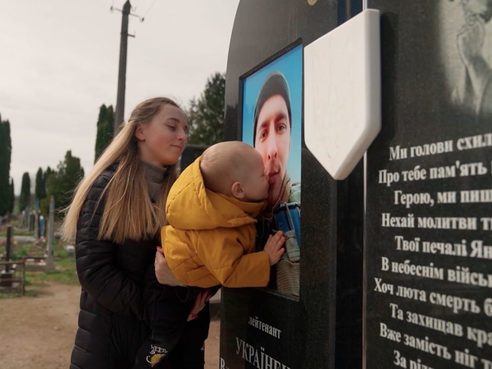Katerinar hält ihren 2-Jährigen Sohn Andrij in den Armen, damit er das Bild auf dem Grabstein seines Vaters küssen kann.