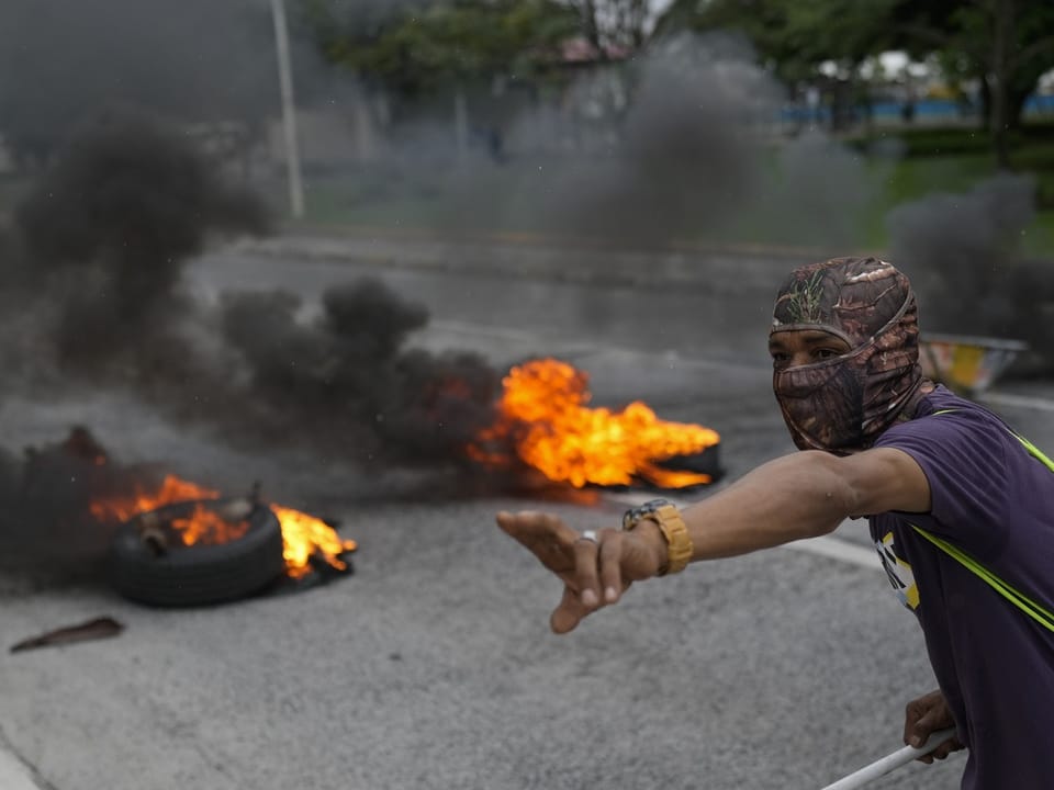Maskierter Mann mit brennenden Reifen.