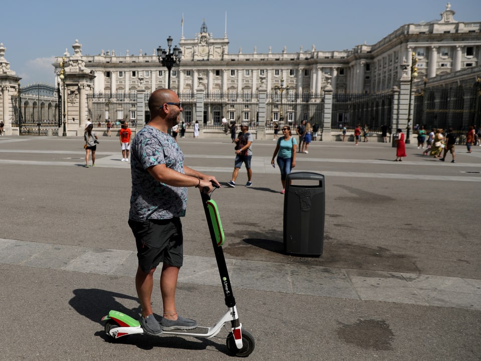 Mann auf E-Roller vor historischem Gebäude.