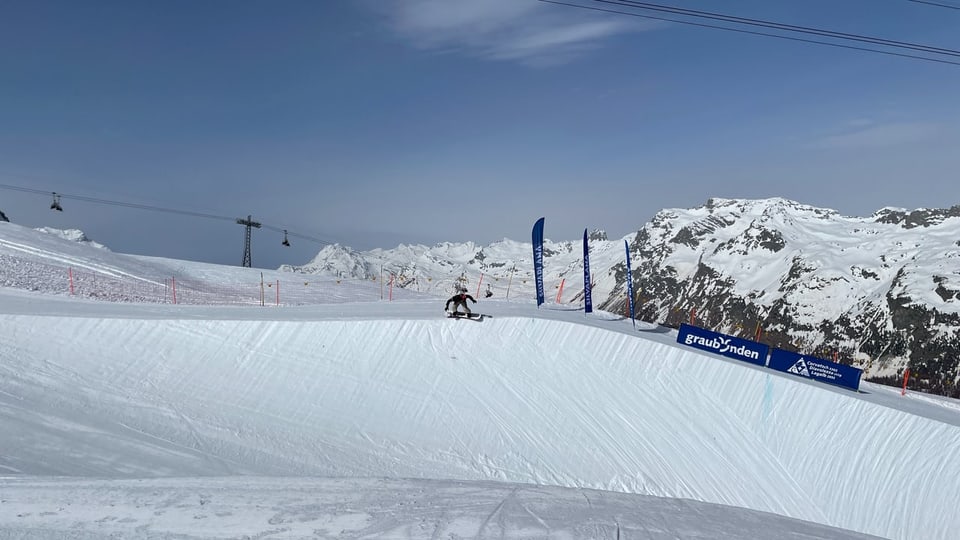 Skifahrer auf schneebedecktem Berg mit Seilbahnen im Hintergrund.