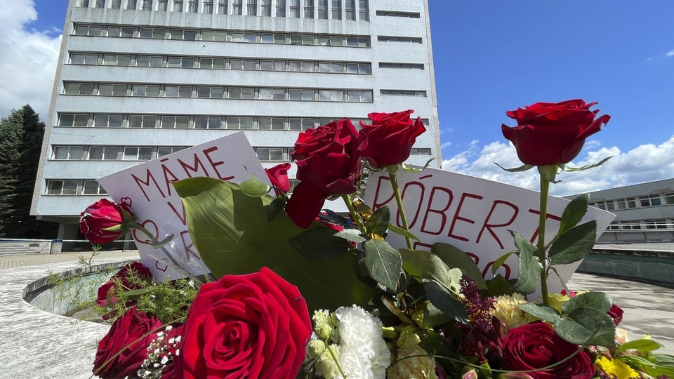 Blumen und Schilder vor einem grossen Gebäude.