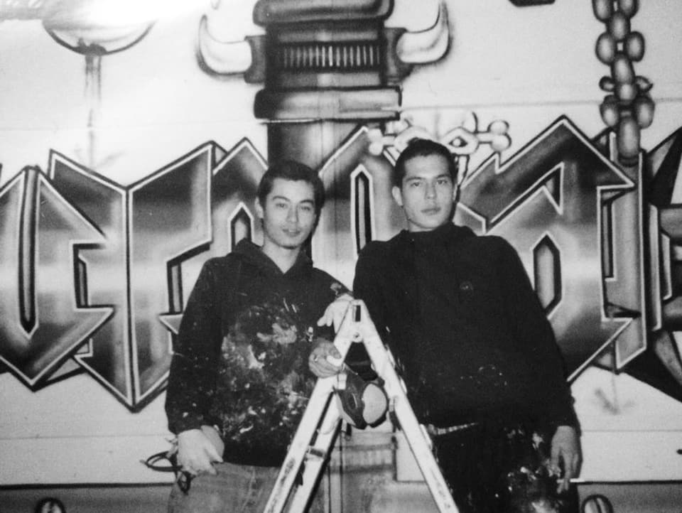 Michi und Tobi Senn auf einer Leiter, hinter ihnen ein Graffiti.