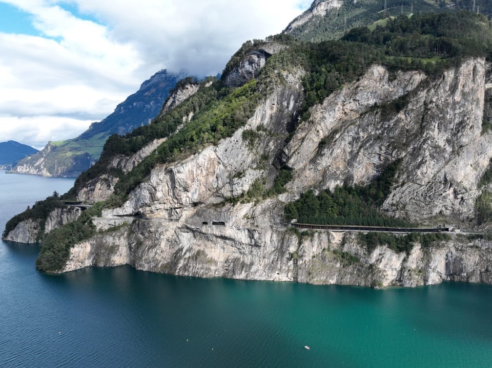 Berglandschaft mit See und Strasse entlang der Felsen.