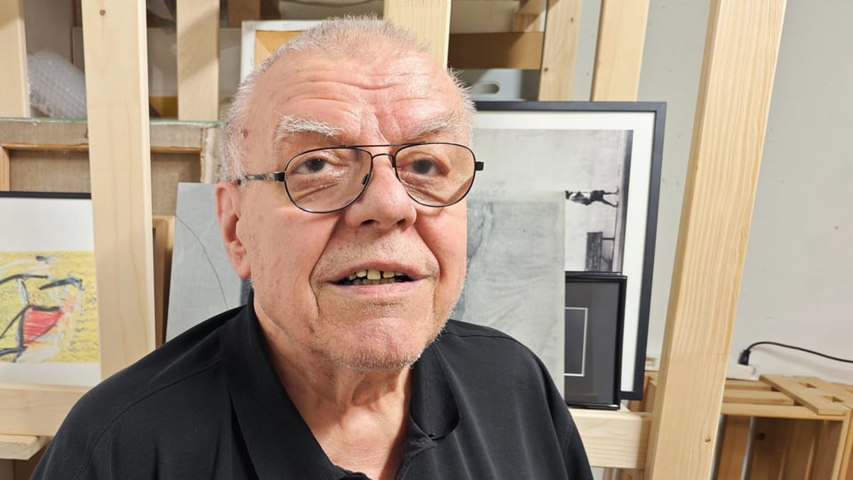 Älterer Mann mit Brille in einem Kunststudio vor Bilderrahmen.