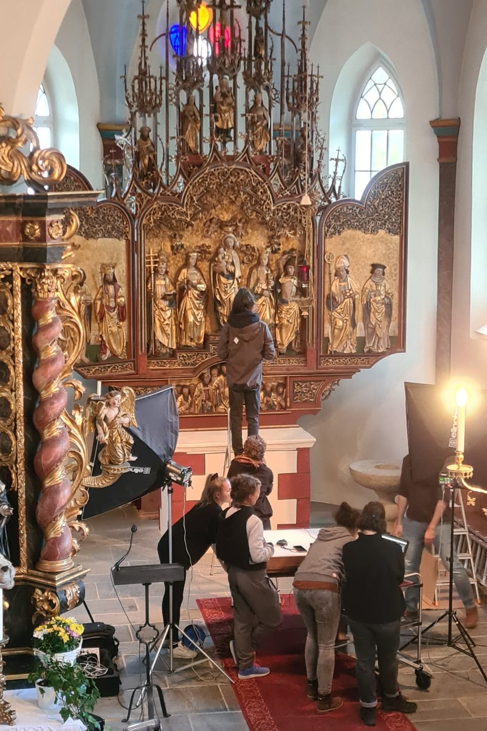 Menschen bei Fotoaufnahmen in einer Kirche mit kunstvollem Altar.