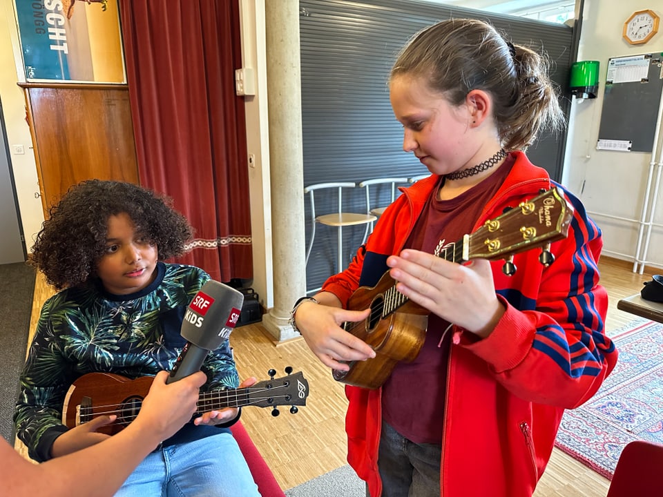 Ein Mädchen zeigt einem Jungen Griffe auf der Ukulele