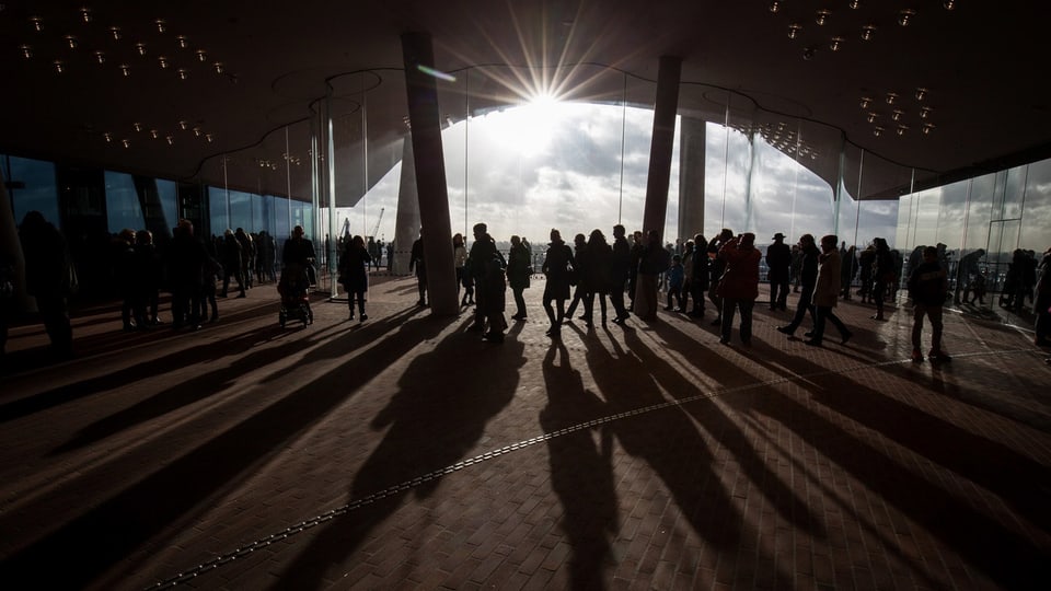 Silhouetten von Menschen vor einem Sonnenuntergang.