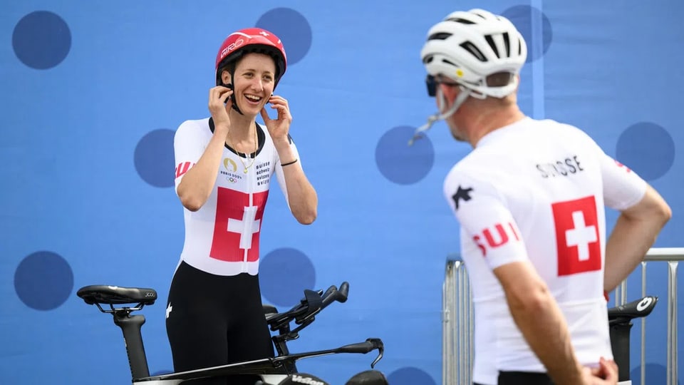 Zwei Radfahrer in Schweizer Trikots sprechen miteinander.