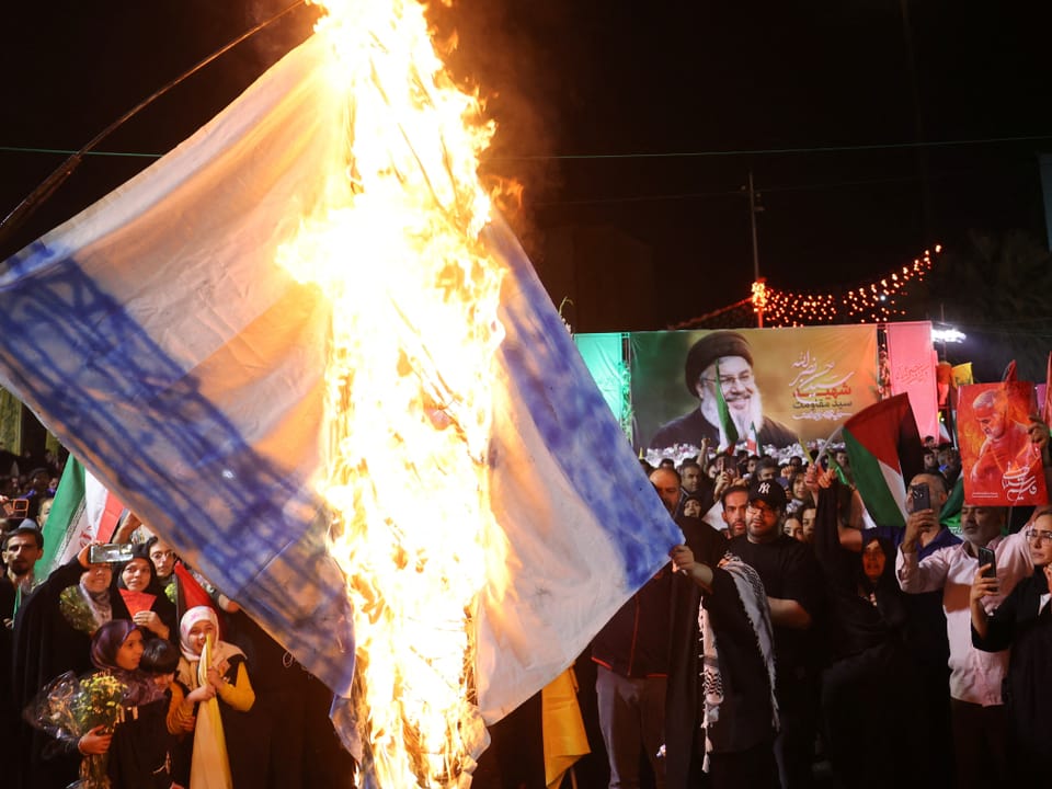 Menschenmenge verbrennt eine grosse Israel-Flagge.