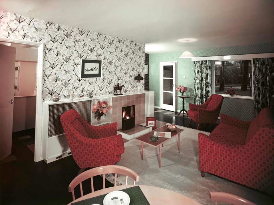 Ein Wohnzimmer mit Blumentapete und Sofagarnitur.