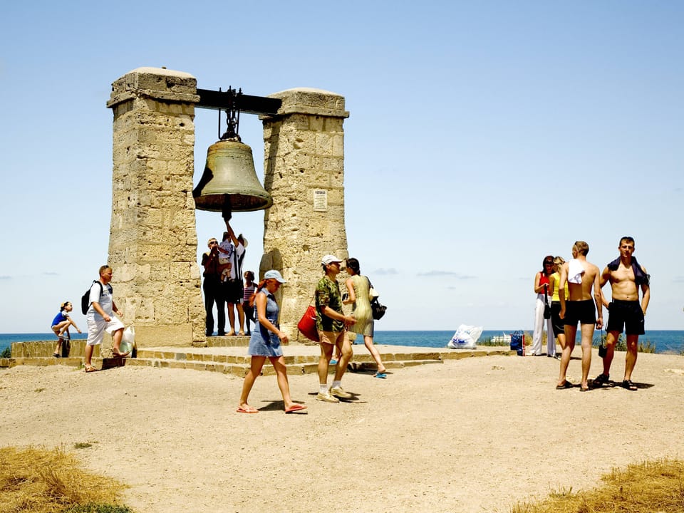 Leute vor einem alten Glockenturm am Strand