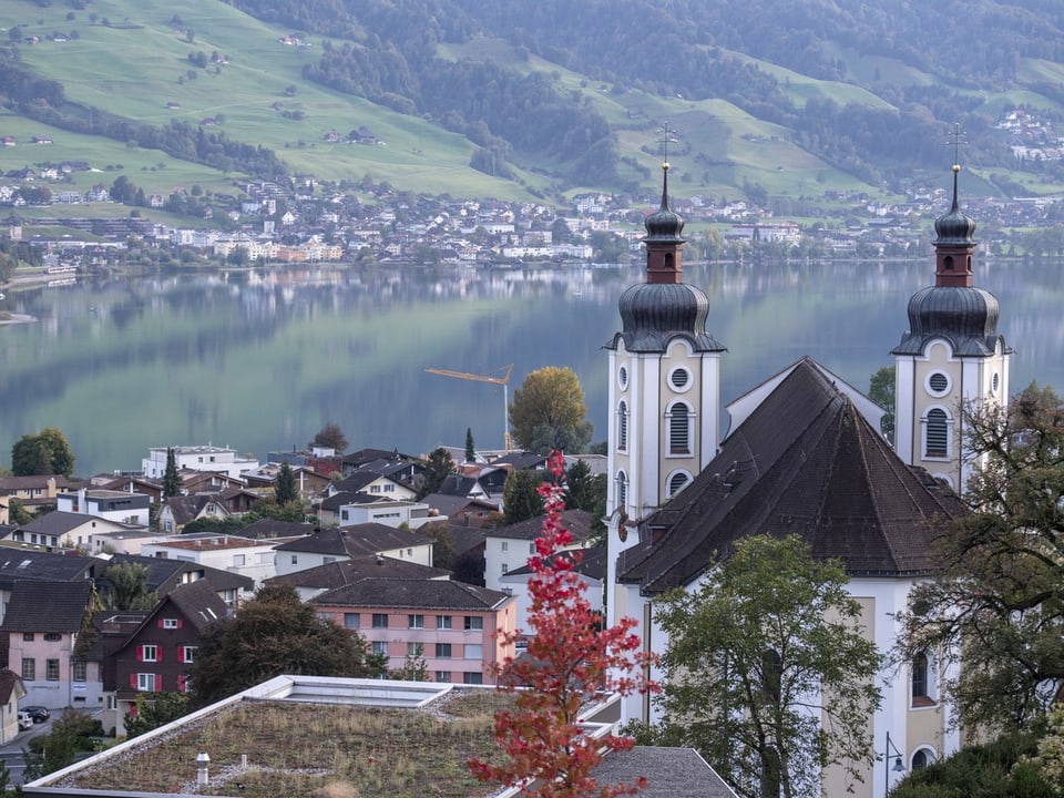 Kirche mit Doppeltürmen vor Sarnersee und Hügeln.