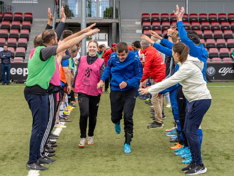 Zwei Reihen mit Fussballspielenden, die eine Welle machen.