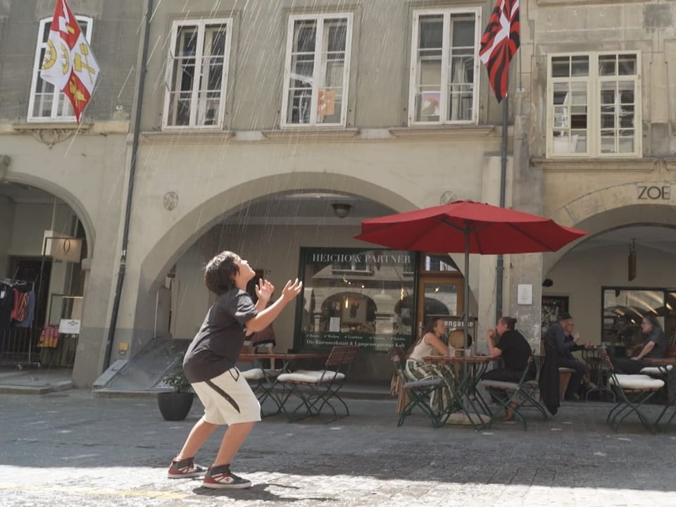 Junger Bub in der Münstergasse, er schaut nach oben zum Speier und wird nass gespritzt