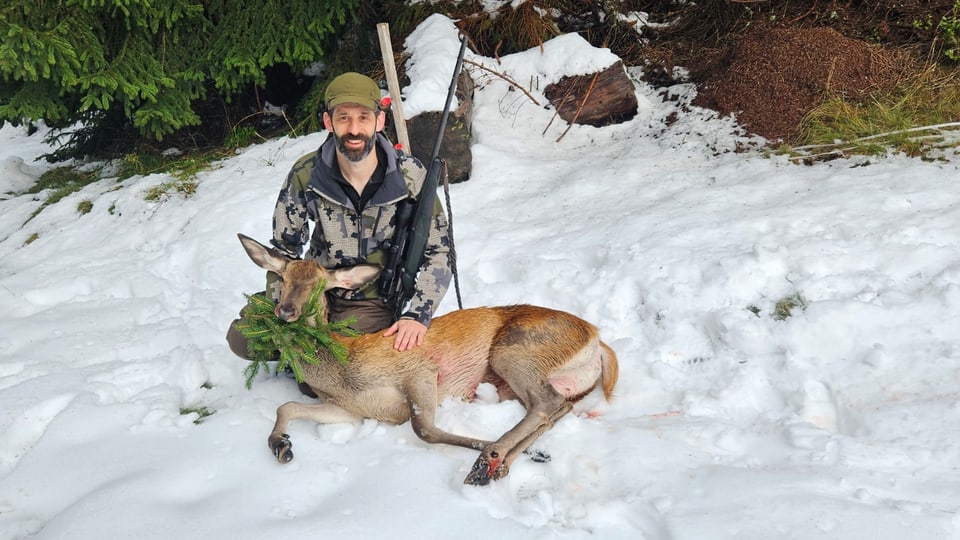 Jäger mit erlegtem Hirsch im Schnee.