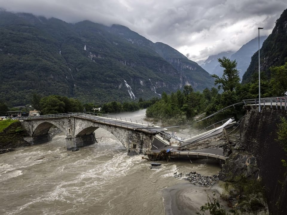 Eingestürzte Brücke über einen reissenden Fluss in einer Berglandschaft.