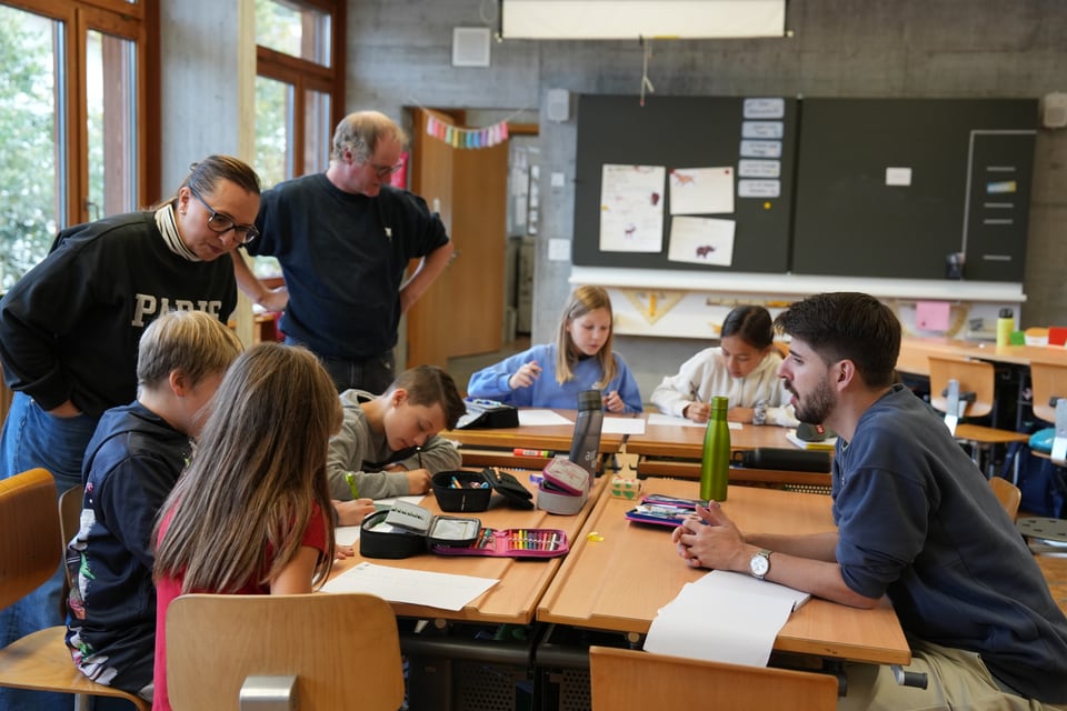 Kinder in einem Klassenzimmer mit zwei Erwachsenen.