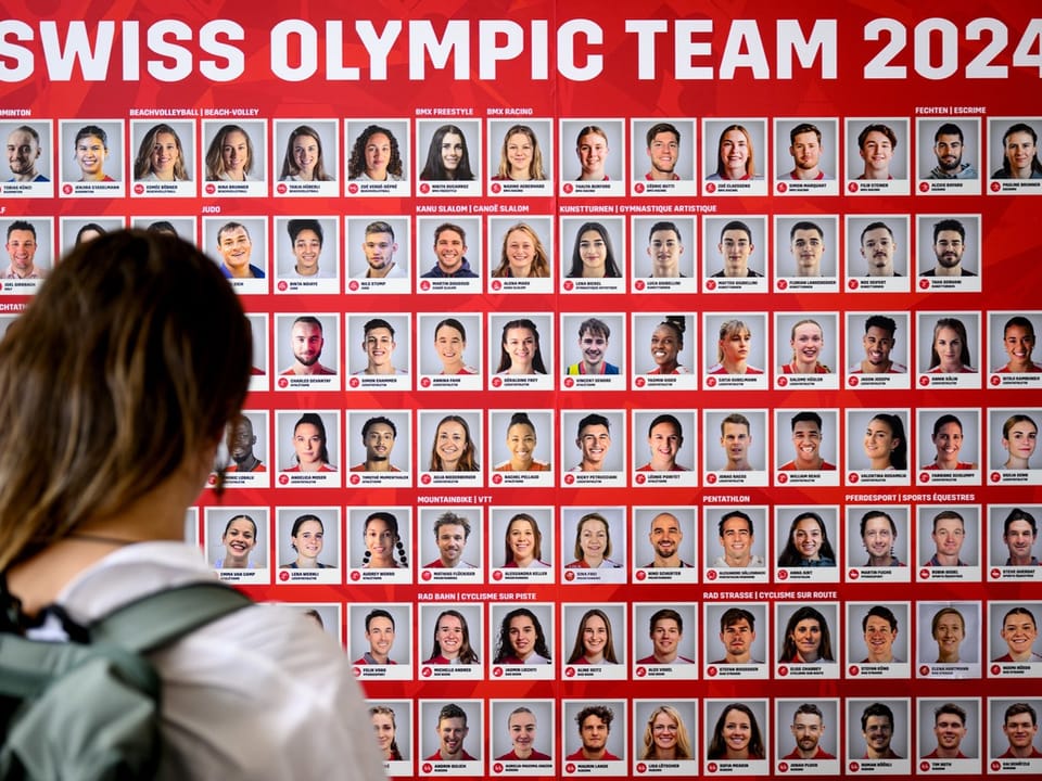 Person betrachtet Wand mit Fotos des Schweizer Olympiateams 2024.
