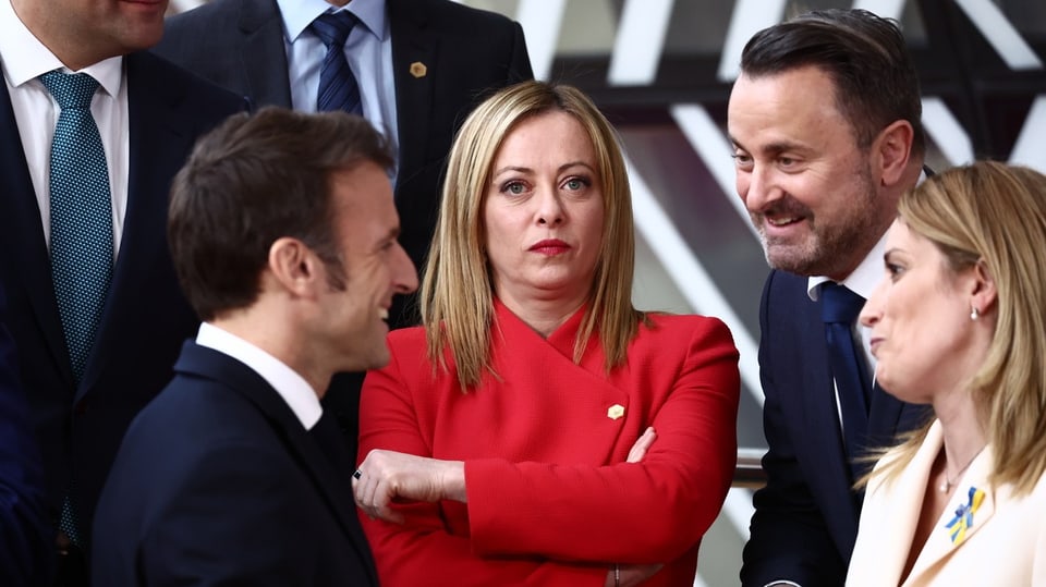 Links der redselige Macron, in der Mitte der eisige Blick von Meloni, die im roten Blazer daherkommt.