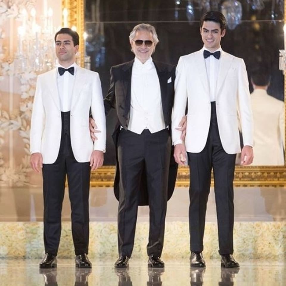 Andrea Bocelli mit seinen Söhnen Amos (links) und Matteo (rechts). Er trägt einen schwarzen Anzug, seine Söhne Weisse Jacketts und schwarze Hosen. 