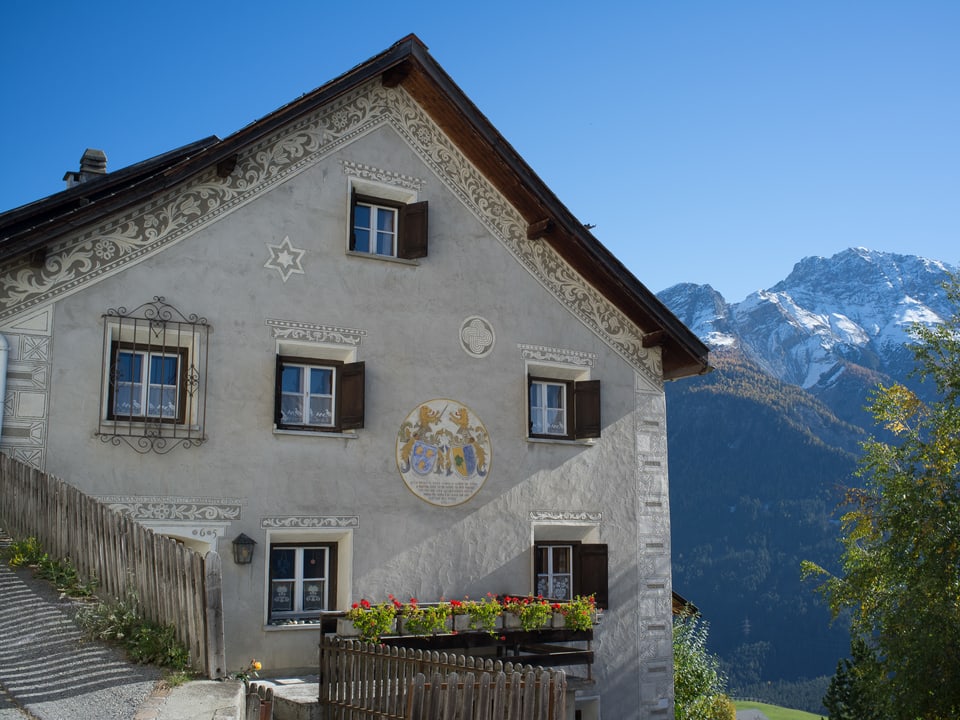 Hausfassade verziert mit Ornamenten im Engadiner Stil.