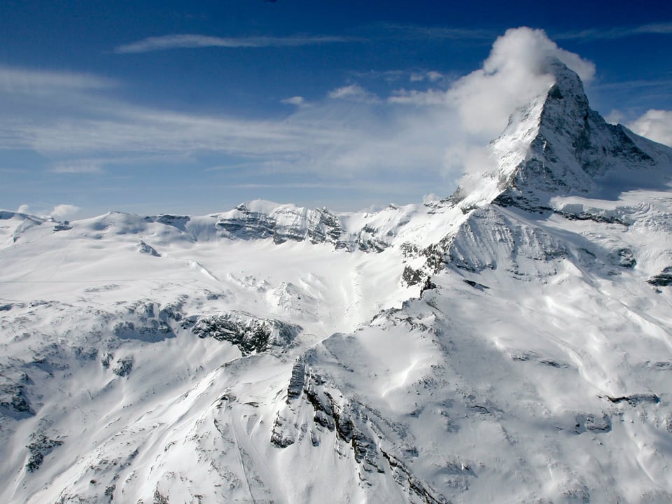 Schneebedeckte Berge mit Matterhorn und blauem Himmel.