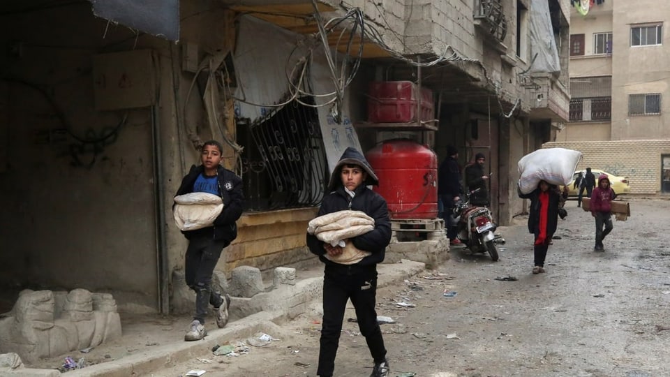 Mehrere Kinder tragen Brot über die Strassen in Damaskus