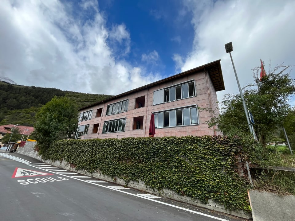 Modernes Gebäude an einer Strasse mit Vegetation im Vordergrund.