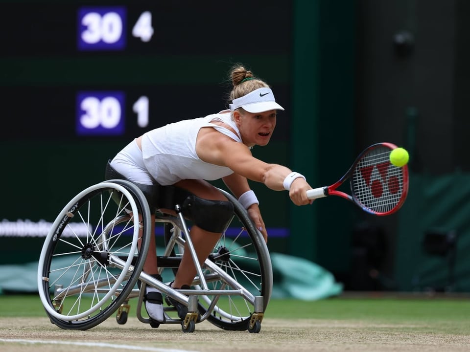 Rollstuhl-Tennisspielerin erreicht einen Ball auf dem Platz.