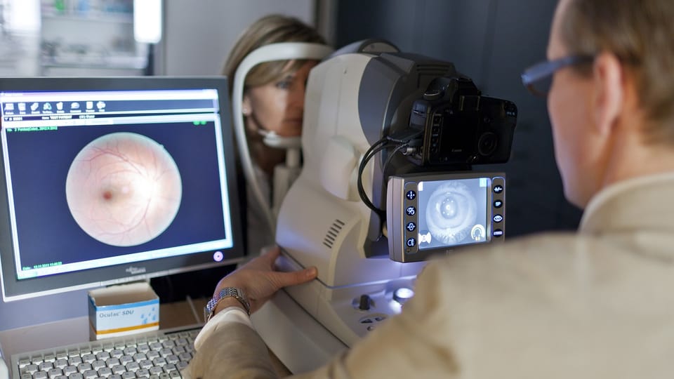 Ein Augenarzt untersucht eine Patientin mittels Fundusfotografie.