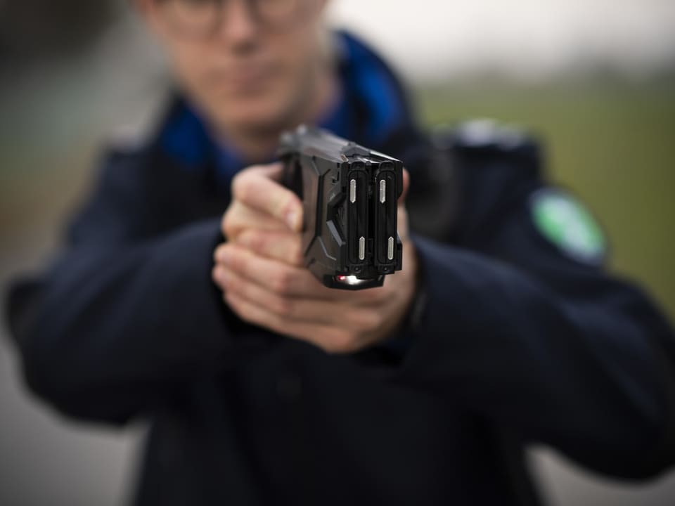 Ein Beamter der Kantonspolizei St. Gallen demonstriert einen Taser.