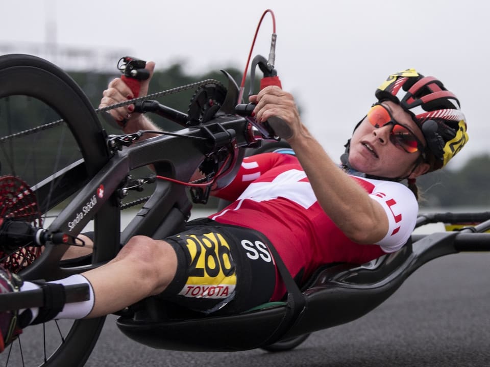 Rennfahrer in der Sitzposition auf Handbike mit Helm und Sportkleidung.