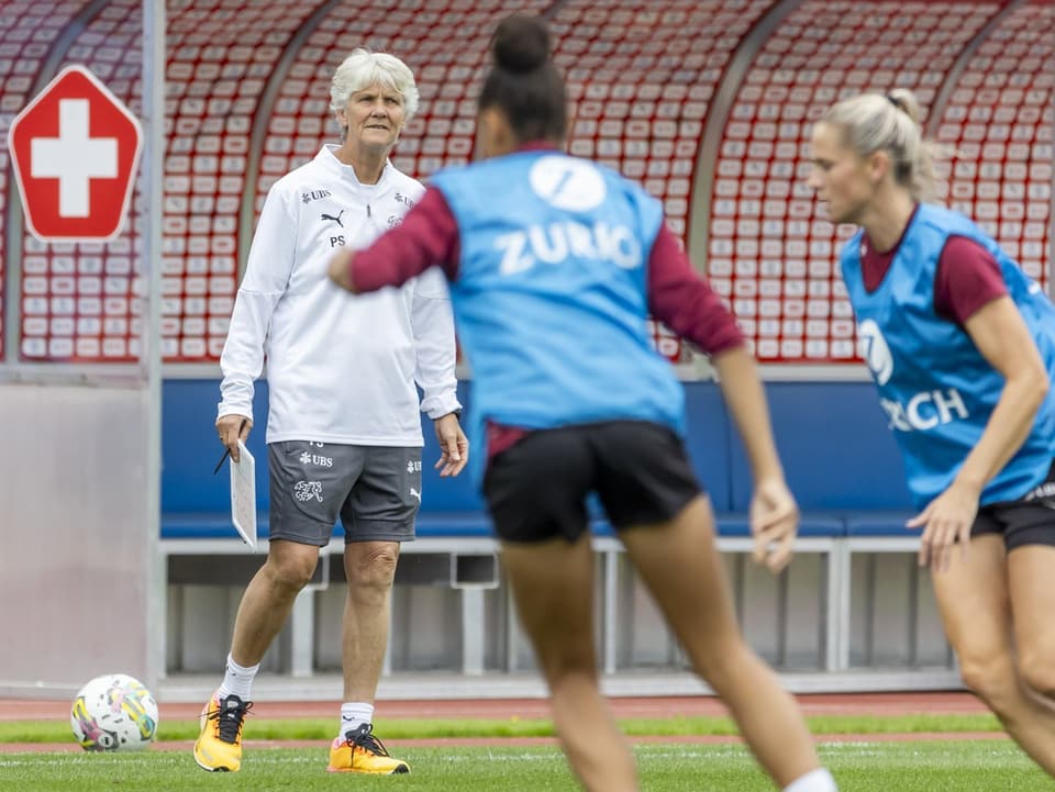 Trainerin beobachtet Fussballspielerinnen im Training.