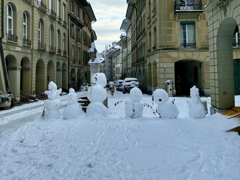 Schneefiguren in der verschneiten Gasse zwischen alten Gebäuden.