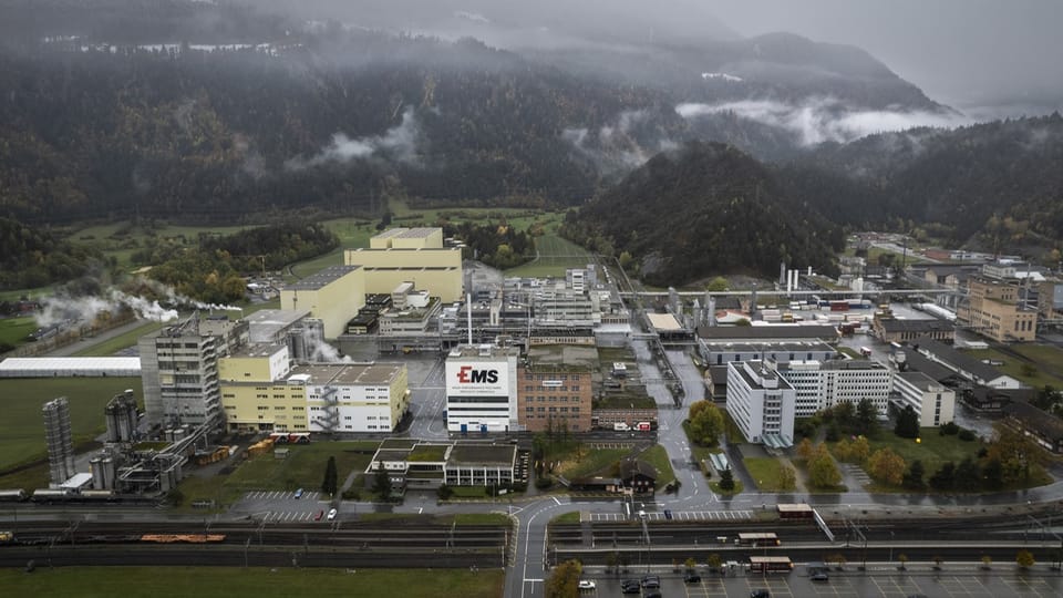 Luftaufnahme einer Industrieanlage umgeben von Bergen und Wäldern.