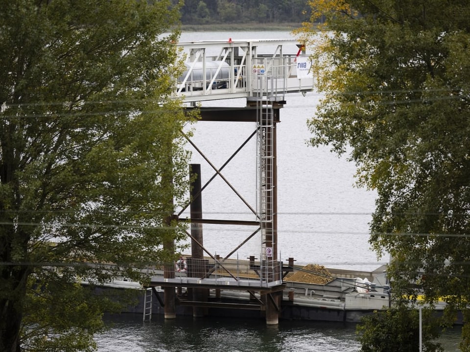 Ein Lastkrahn auf dem Bielersee. Aushubmaterial fällt vom Förderband auf den Krahn.