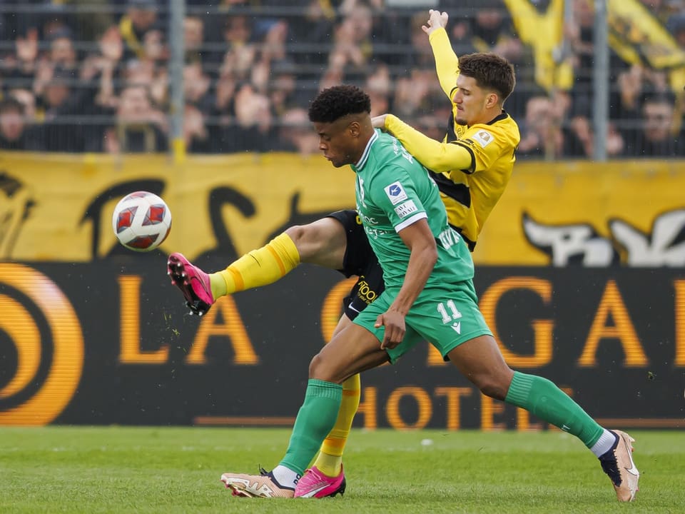 Zwei Fussballspieler kämpfen um den Ball auf dem Spielfeld.