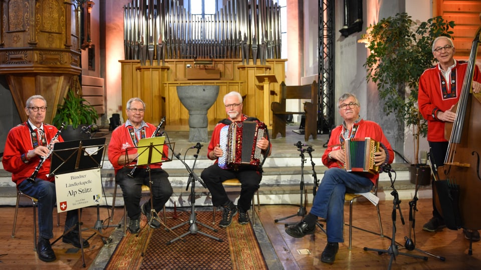 Ländlerkapelle Alp Stätz, zu fünft, alle mit roter Sennenkutte und ihren Instrumenten.