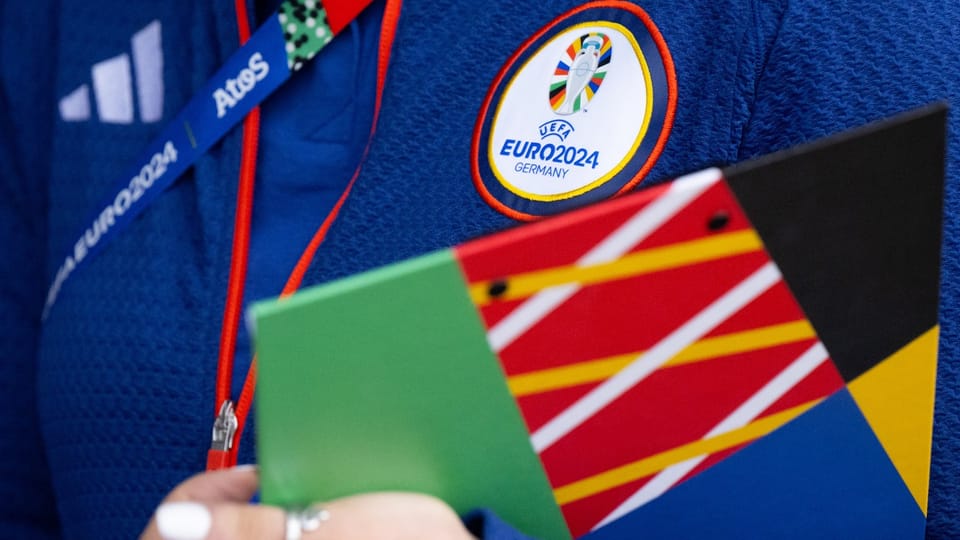 Nahaufnahme eines EURO 2024 Abzeichens auf blauer Kleidung und einer bunten Mappe.